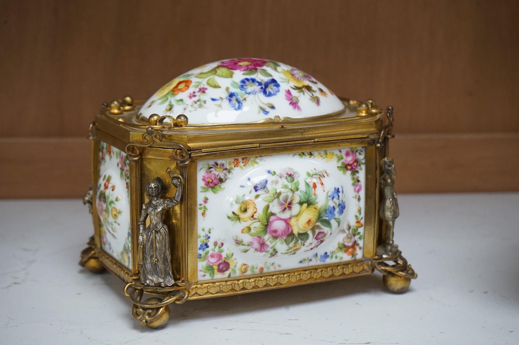 A gilt-brass figural and floral porcelain jewellery casket, 14cm wide, 11cm high.